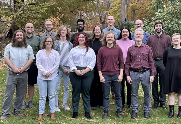 A group photo of the faculty of the College of Music. The group stands outside in three rows, smiling at the camera.